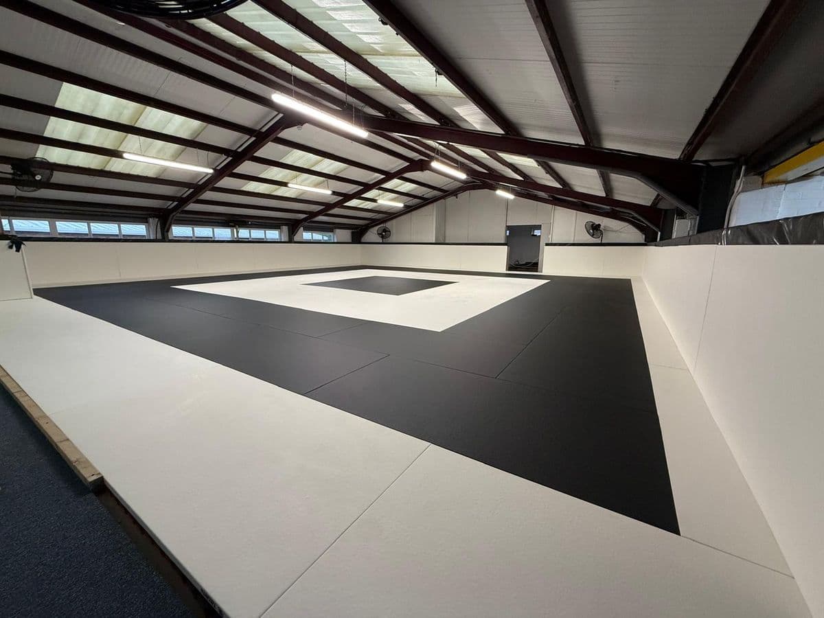 The mat room at SWBJJ: a full-size black and white competition mat under a pitched roof